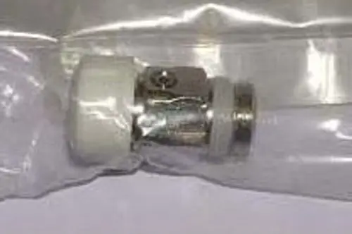 Ersatzteil von Remeha, das in einer transparenten Verpackung präsentiert wird. Es handelt sich um ein Metall- und Kunststoffelement, möglicherweise für ein Heizsystem.